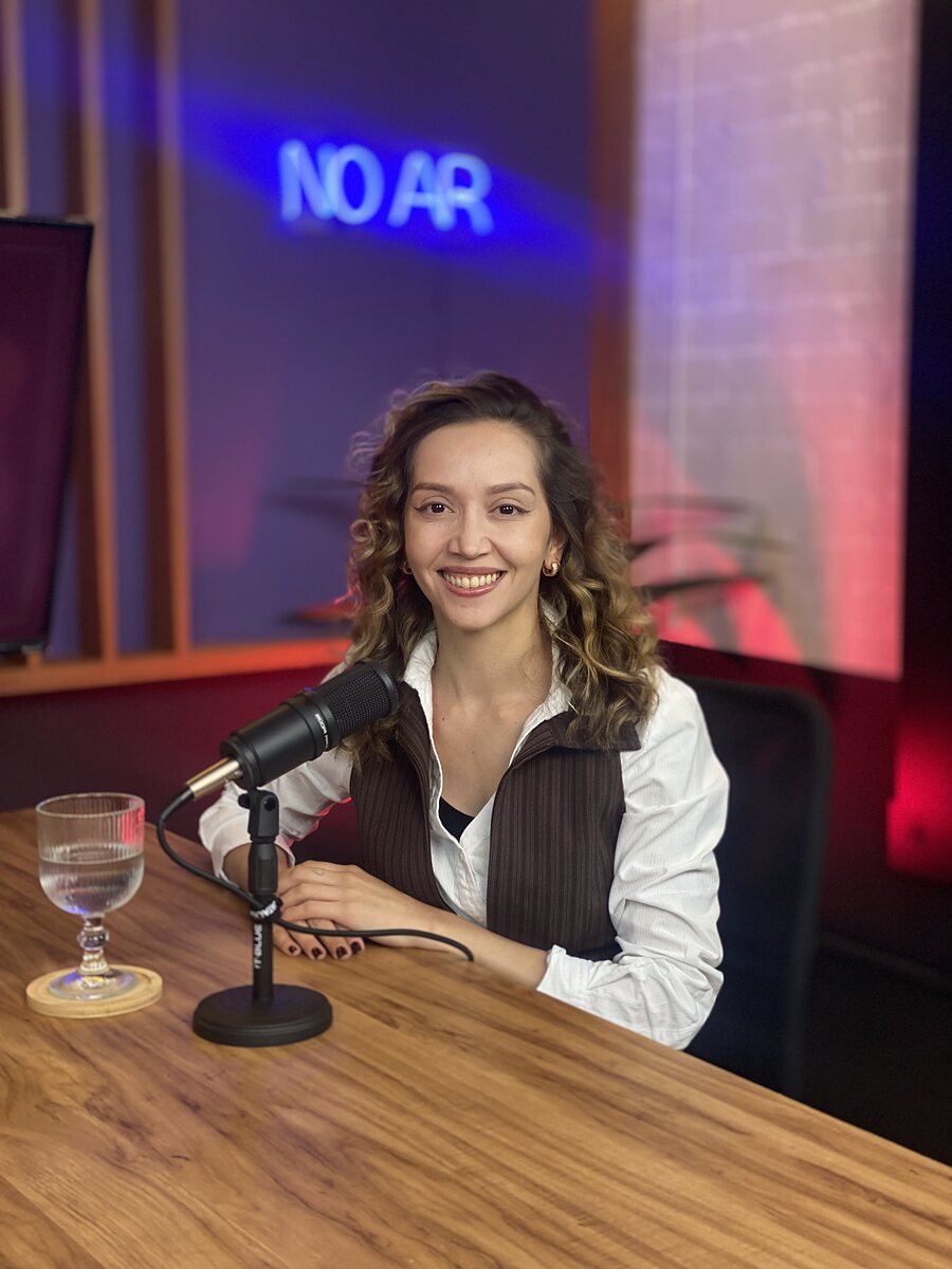Deyse Schultz no estúdio de podcast, diante do microfone